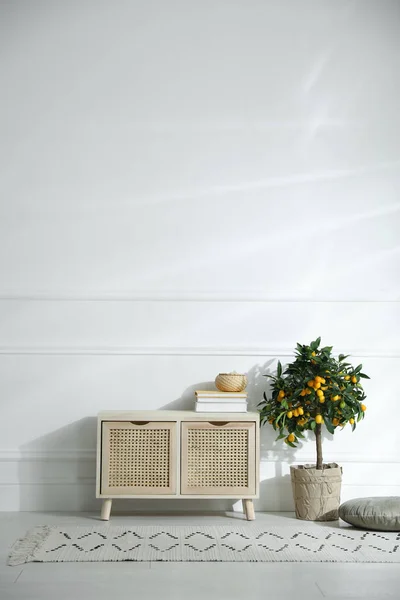 Wooden commode near white wall in room. Interior design