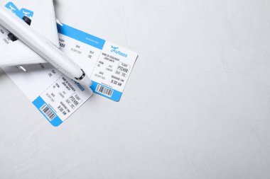 Oyuncak uçak ve gri arka planda biletler, mesaj için yeri olan düz bir yer. Seyahat acentası kavramı