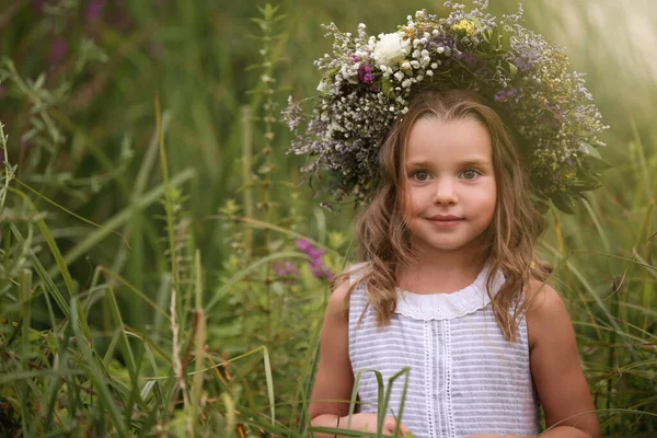可愛いです女の子はフィールドで美しい花で作られた花輪を着て — ストック写真