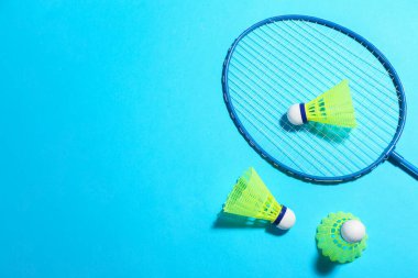 Badminton raketi ve açık mavi arka planda mekik horozu, düz yatış. Metin için boşluk