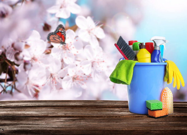 Различные моющие средства и принадлежности на деревянном столе, место для текста. Весенняя уборка