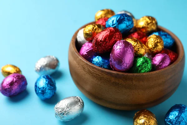 Ciotola Legno Con Uova Cioccolato Avvolte Foglio Colorato Sfondo Azzurro — Foto Stock