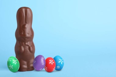 Çikolata tavşanı ve açık mavi arka planda Paskalya yumurtaları, metin için yer