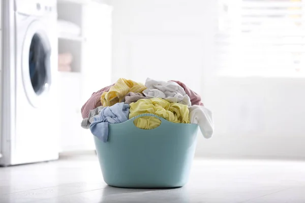 Light blue basket with dirty laundry on floor indoors