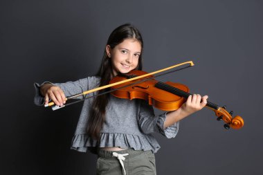 Siyah arka planda keman çalan küçük kız