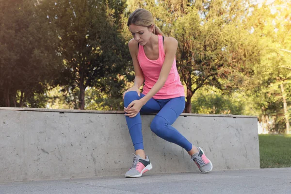 公園で膝の問題を抱えているスポーツウェアの若い女性 — ストック写真