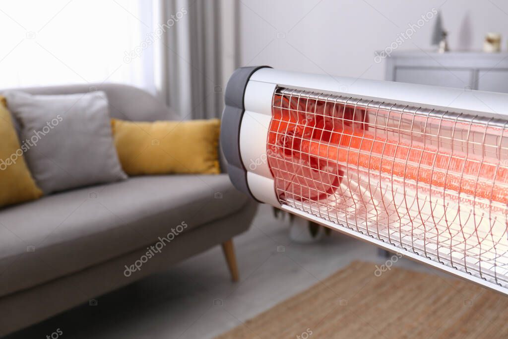 Modern electric infrared heater in room, closeup. Space for text