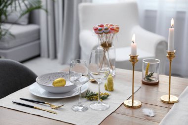 Güzel Paskalya sofrası, yanan mumlar ve kapalı mekanda çiçek dekoru.