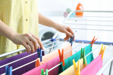 Kadın temiz çamaşırları banyodaki kurutma askısına asıyor.