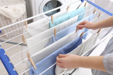Kadın temiz çamaşırları banyodaki kurutma askısına asıyor.