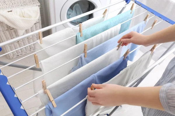 Kadın temiz çamaşırları banyodaki kurutma askısına asıyor.