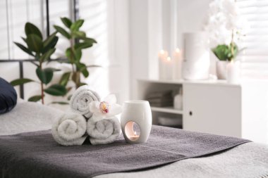 Havlular, aroma lambası ve orkide çiçeği kaplıca salonundaki kanepede.