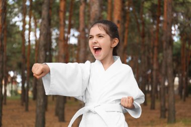 Kimonolu tatlı küçük kız ormanda karate yapıyor.