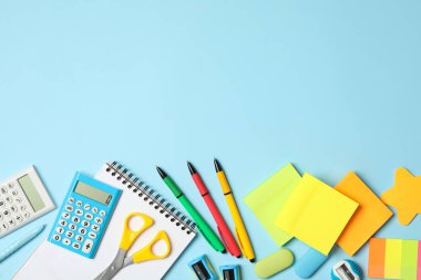 Açık mavi arkaplanda farklı kırtasiye malzemesi, metin için boş alanı olan düz bir yer. Okula geri dön.