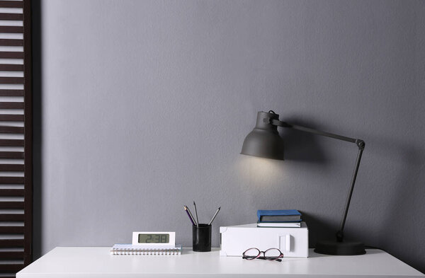 Lamp and different stationery on table in office. Space for text