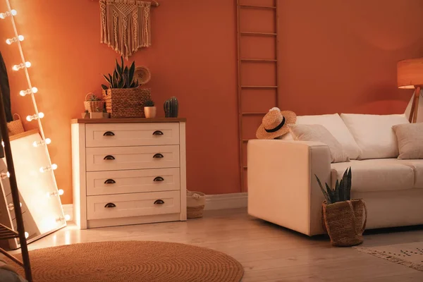 Large mirror with light bulbs and chest of drawers in stylish room interior