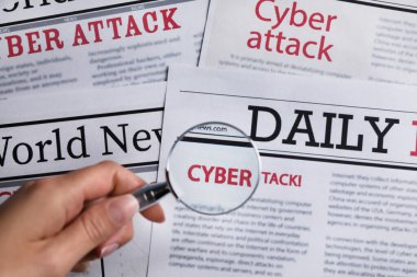 Gazete başlığı CYBER HATTACK ile okumak için büyüteç kullanan kadın, üst görünüm