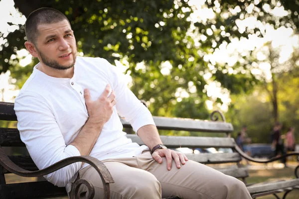 Kalp krizi geçiren bir adam parkta bankta oturuyor.