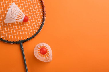 Badminton raketi ve turuncu arka planda mekik horozu, düz yatış. Metin için boşluk