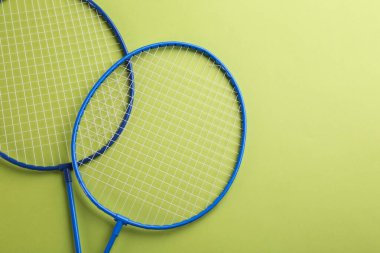 Açık yeşil zemin üzerinde Badminton raketleri, düz yatıyordu. Metin için boşluk