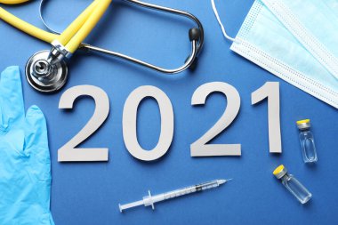 Koronavirüs aşısıyla düz kompozisyon ve mavi zemin üzerinde 2021 numara.