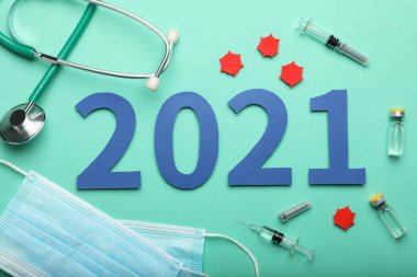 Koronavirüs aşısıyla düz kompozisyon ve turkuaz arka plan 2021 numara.