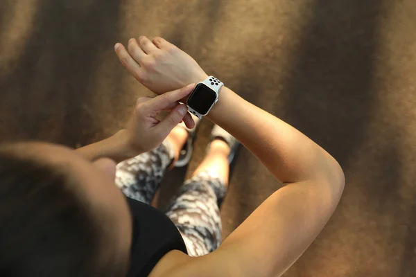 Woman using modern smart watch during training outdoors, top view