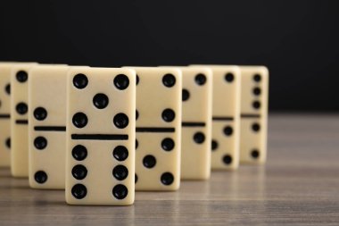 Tahta masadaki Domino fayansları siyah arka plana karşı, yakın plan. Metin için boşluk