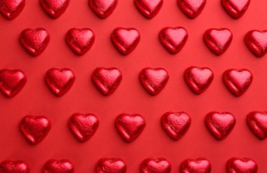 Kırmızı arka planda kalp şeklinde çikolata şekerlemeleri, düz yatış