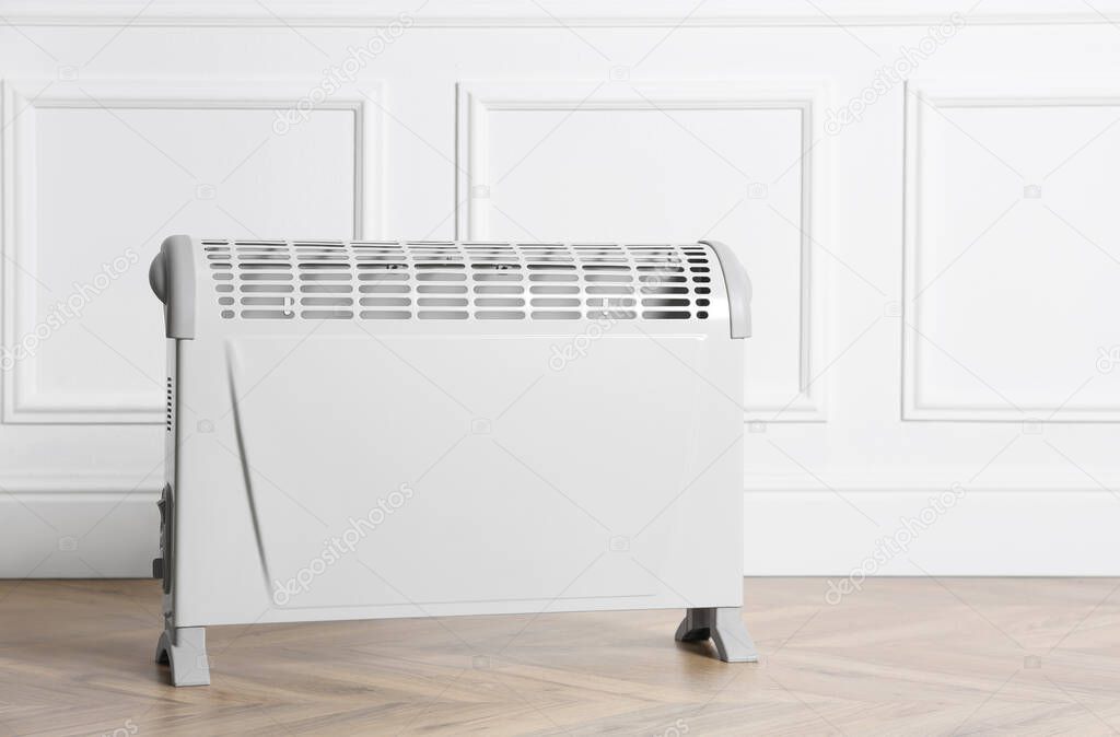 Modern electric convection heater on floor in room, space for text