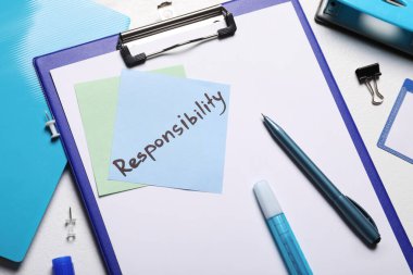 Beyaz masadaki ofis malzemelerinin sorumluluğunu içeren mavi bir not.