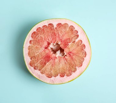 Açık mavi zemin üzerinde taze kesilmiş pomelo meyvesi, üst görünüm