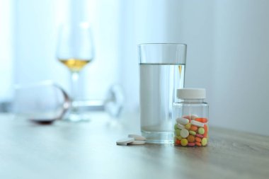 İçerideki masada bir bardak su ve haplar, mesaj için yer. Akşamdan kalma ilacı.