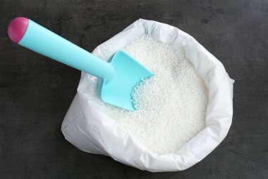 Granüler mineral gübreli çanta ve gri arka planda kepçe, üst görünüm