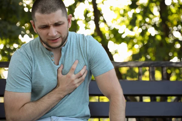 心脏病发作的男子坐在公园的长椅上 — 图库照片