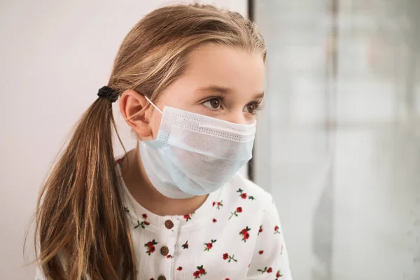 Niña Triste Con Máscara Protectora Mirando Por Ventana Interior Permanecer — Foto de Stock