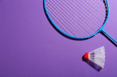 Badminton raketi ve mor arka planda mekik horozu, düz konum. Metin için boşluk
