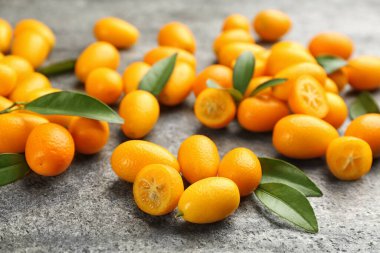 Taze olgun kumkatlar ve gri masada yapraklar.