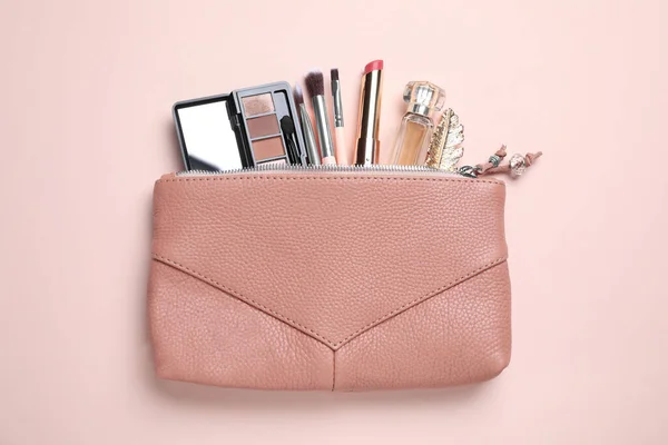 Makeup products with cosmetic bag on pink background