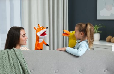 Anne ve kızı evde kukla gösterisi yapıyorlar.