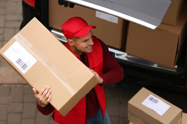 Courier with parcel near delivery van outdoors, above view