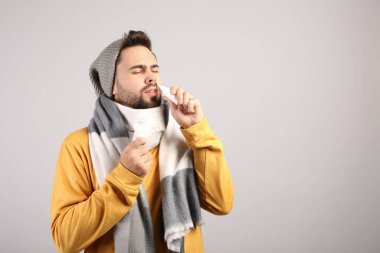 Açık gri arkaplanda burun spreyi kullanan adam, metin için boşluk