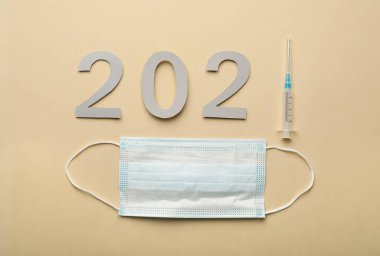 2021 şırıngalı kağıt numaraları ve bej arka planda tıbbi maske. Coronavirus aşısı