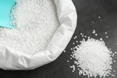 Granüler mineral gübreli çanta ve gri arka planda kepçe, yakın plan
