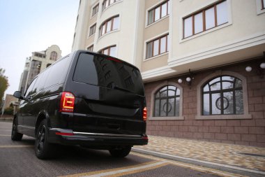 Siyah minibüs binanın yakınına park edilmiş.