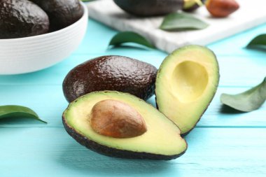 Turkuaz ahşap masada yeşil yapraklı avokadolar, yakın plan.