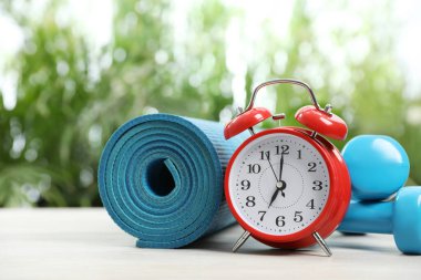 Çalar saat, halterler ve yoga minderi açık havada, mesaj için yer var. Sabah egzersizi