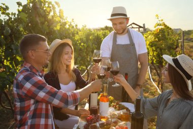 Şarap bardakları tutan ve üzüm bağında eğlenen arkadaşlar.