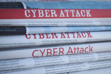Arkaplan olarak CYBER saldırısı manşetlerinin olduğu yığılmış gazeteler, yakın plan