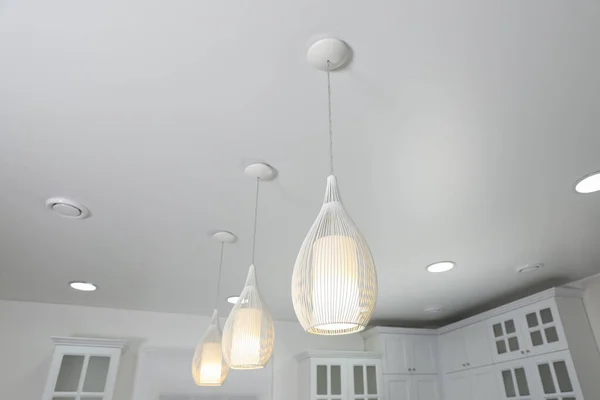 Modern pendant lamps on white ceiling indoors